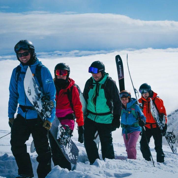 a group of skiers and splitboarders hike through the snow above the clouds with their ski guide in furano hokkaido japan