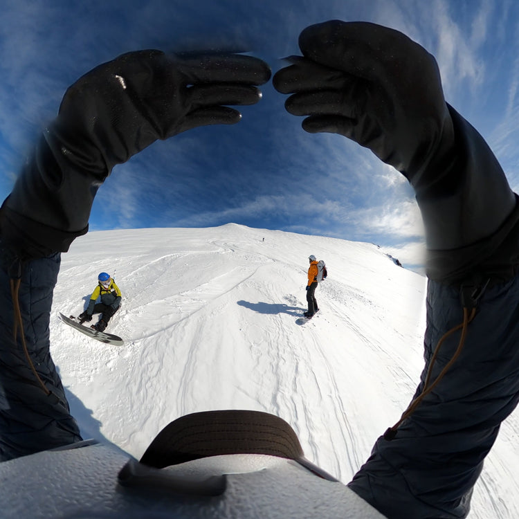A group of skiers and splitboarders ride in east greenland with the ski guide giving the signal to go ahead by raising circled arms