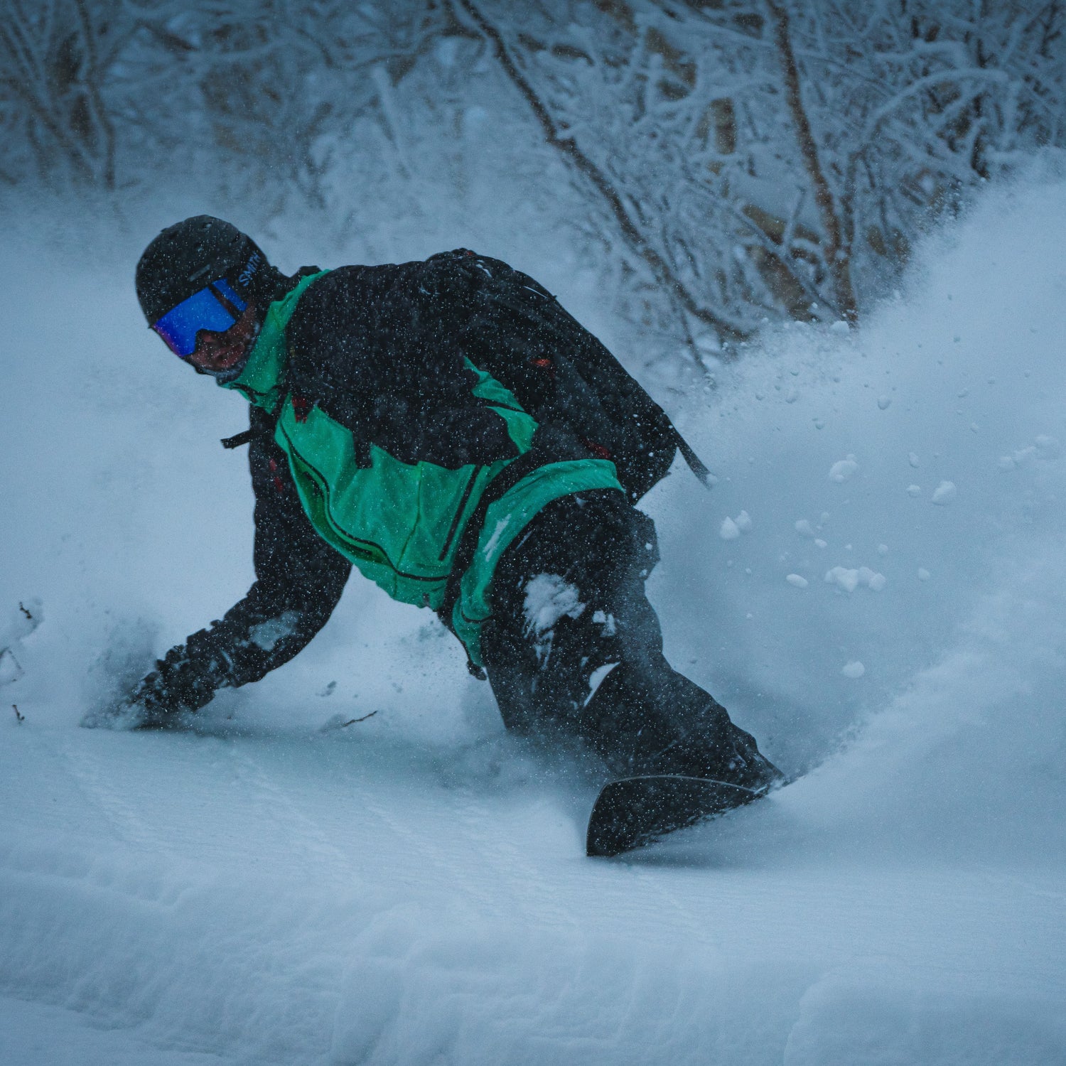 a snowboarder takes a toeside turn sparying snow on a ski guide trip in furano hokkaido japan