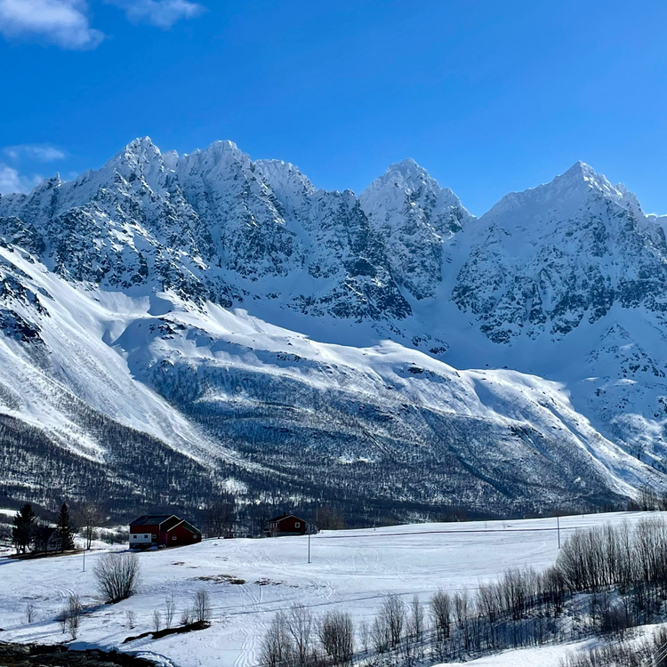 Houses sit below steep snowy couloirs on the Lyngen Peninsula in Norway