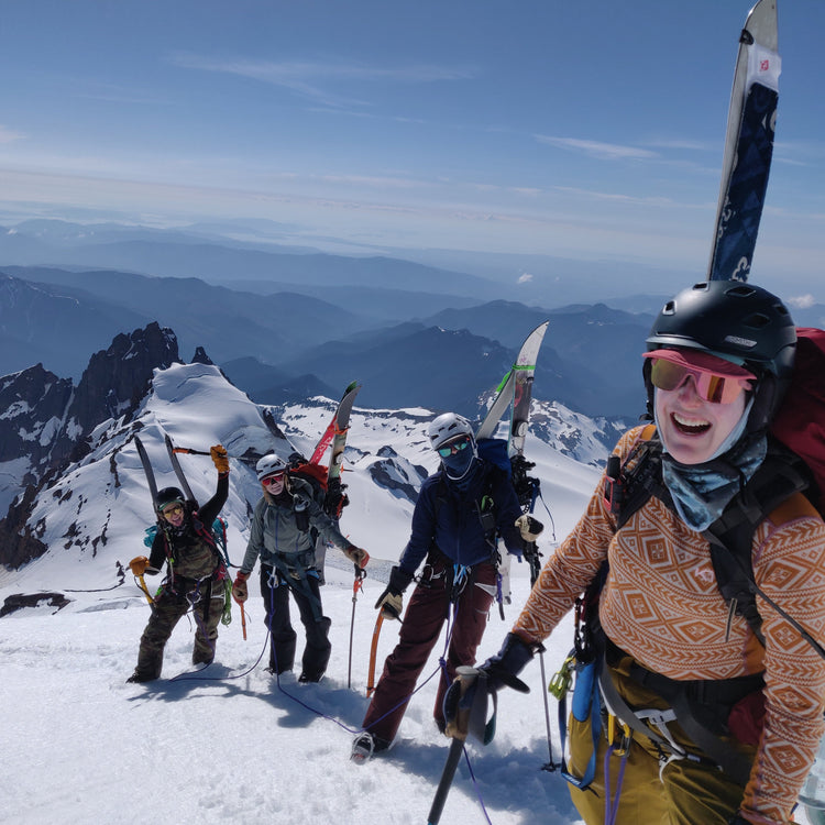 4 women with crampons, splitboards, and ice axes climb above colfax peak, the twin sisters, and bellingham while going up the pumice ridge and the roman wall on the coleman and deming glaciers on mount baker during the womens splitboard mountaineering course