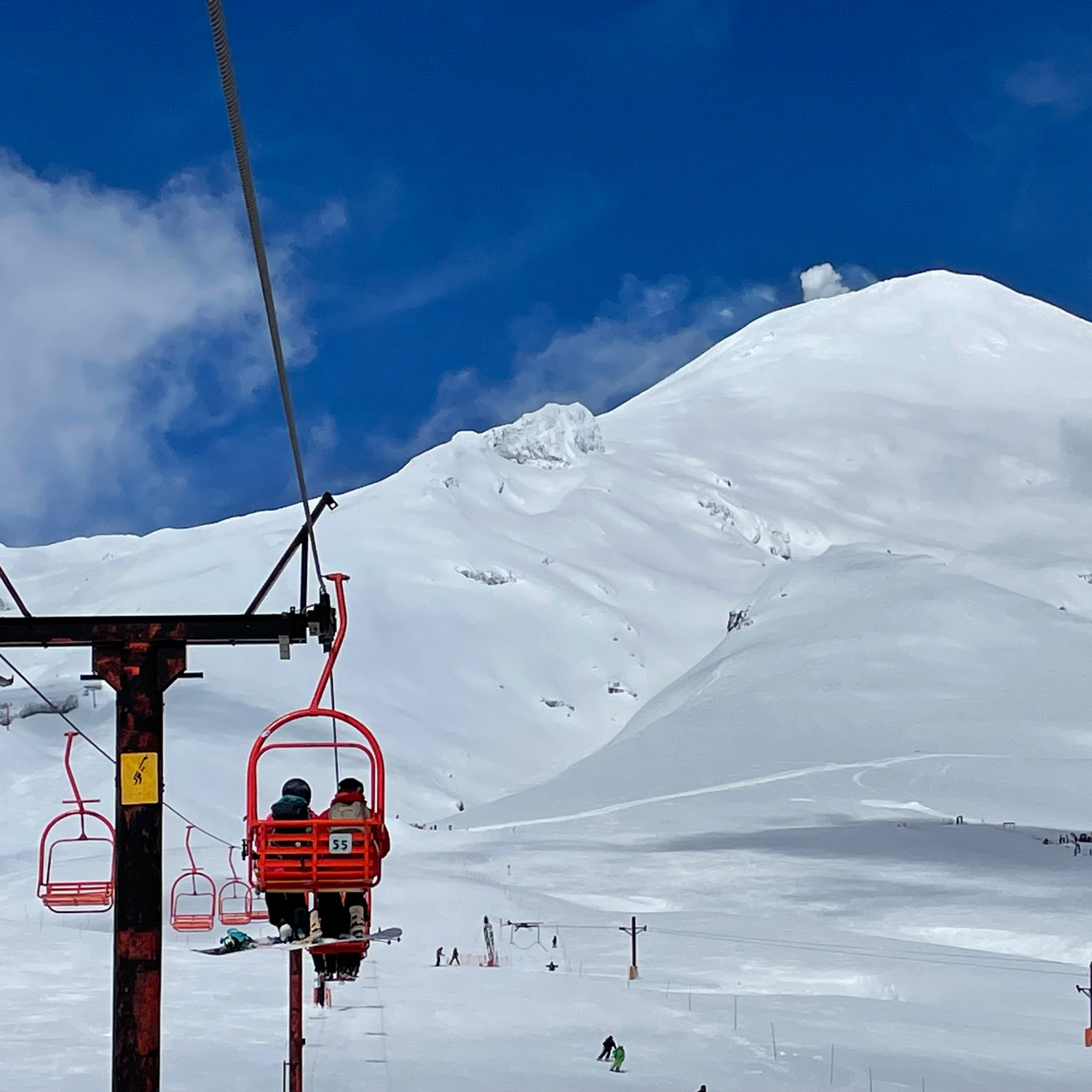 skiers and snowbaorders ride a ski lift at villarica ski area as the volcano smokes above pucon chile