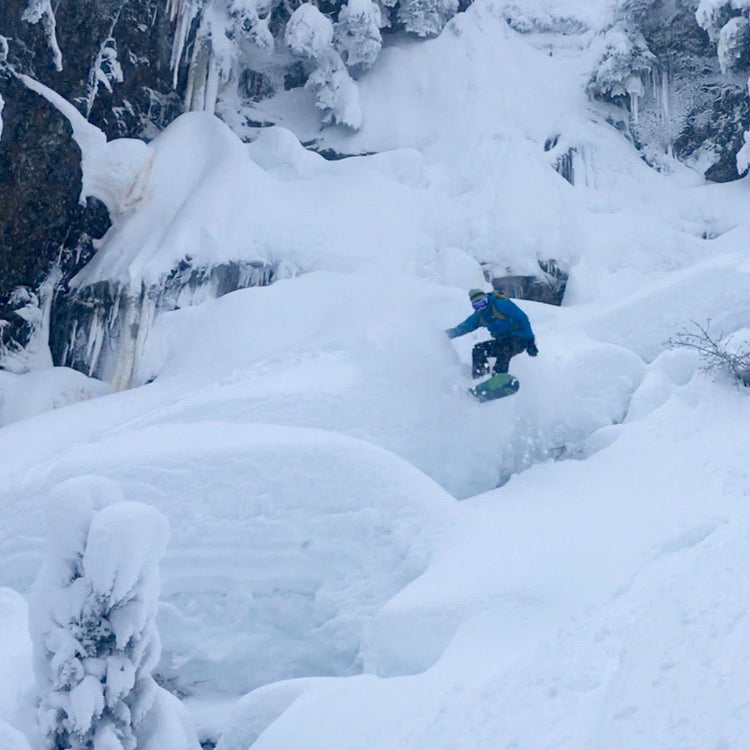 A snowboarder jumps of pillows of snow in the Mount Baker Backcountry during an advanced tour.