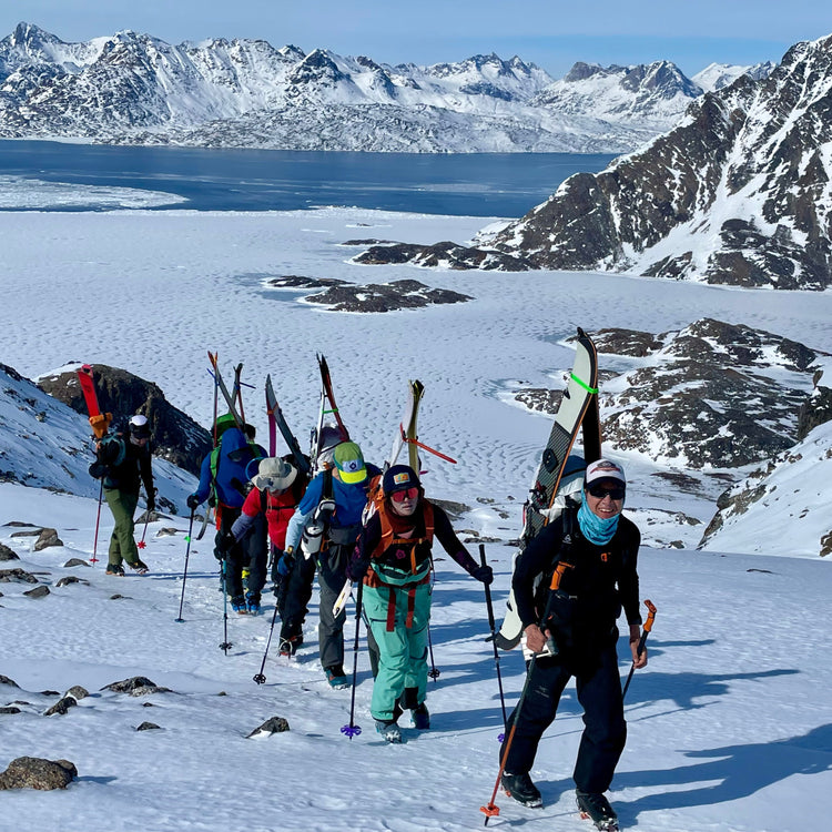 ski touring and splitboarding hike above a frozen fjord during a guided week long ski trip using crampons and backpacks