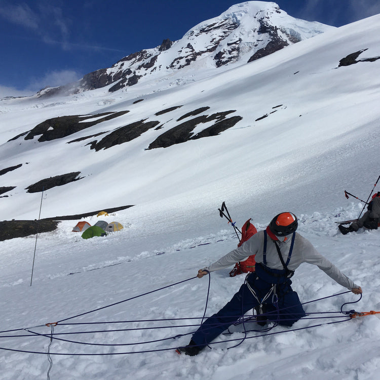 Climber practices Crevasse recuse systems on the side of Mount Baker with the mountain in the background.