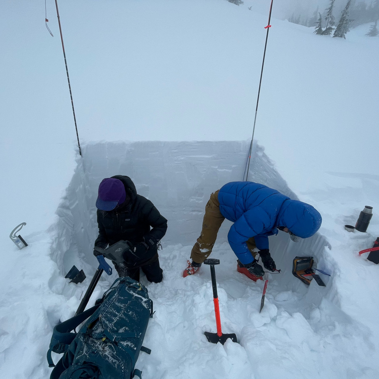 Two AIARE 2 students in their snow pit recording observations and findings.