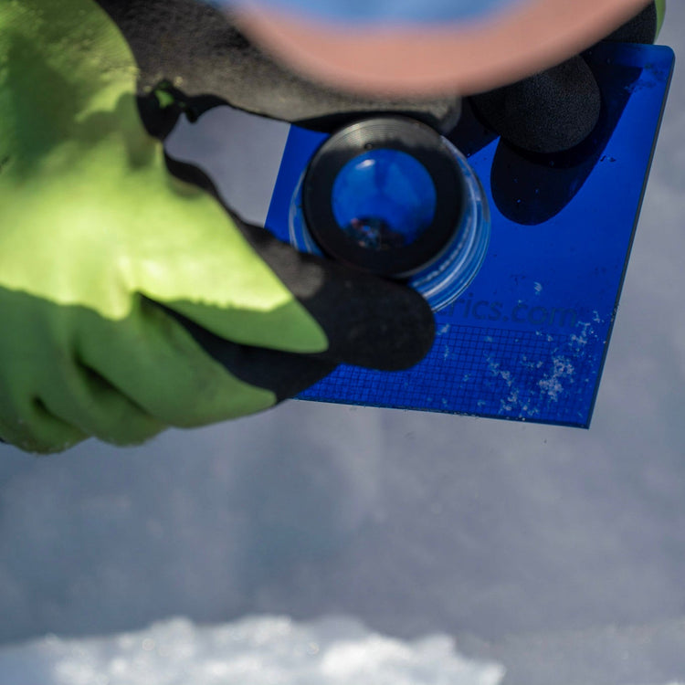 This is what looking at individual snow grains is like. Snow is on the blue plastic crystal card and you look at the grains through a magnifying glass called a loupe.