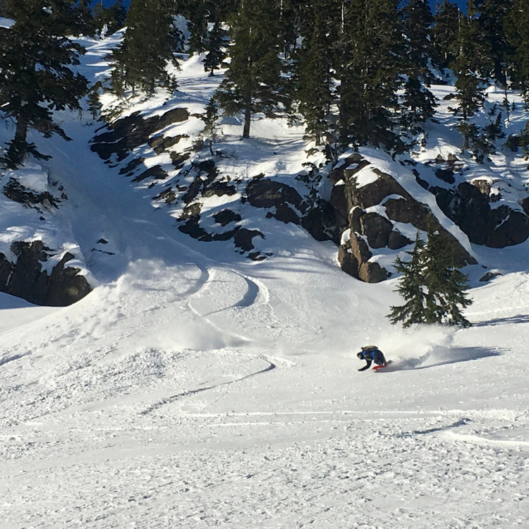 A splitboarder making a deep turn coming out of a rocky chute. During the Advanced Splitboard course we ride a variety of terrain!