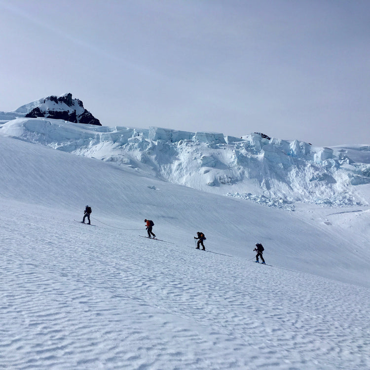 On the ski mountaineering course the group of four move through glaciated terrain on a rope.