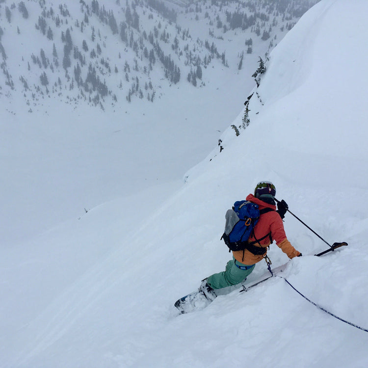 woman splitboard mountaineering rides while being ski belayed on steep terrain in the mt baker backcountry