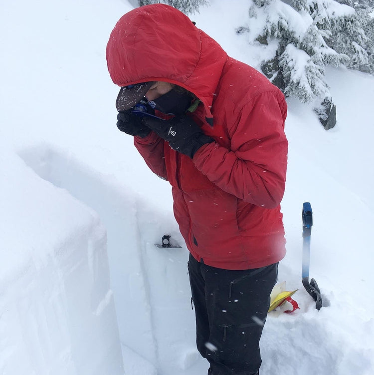 Looking at snow crystals with a loupe to see the shape and size of the snow. Identifying layers in the snowpack during an AIARE 2 course in the Mount Baker backcountry.