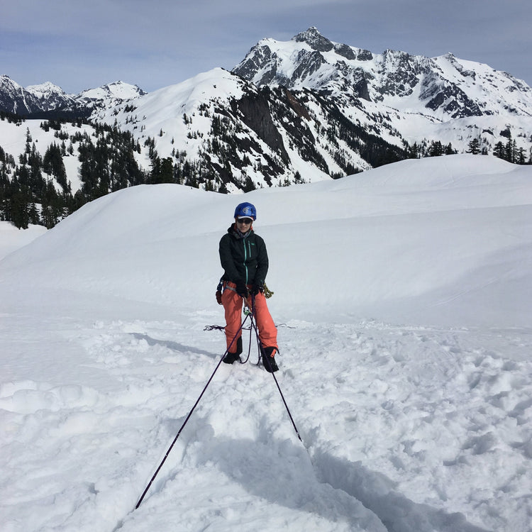 a woman hangs on a rope around snow boallard while testing and learning during the only womens splitboarding program in the north cascades washington seattle