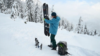 A splitboarder transitions to downhill in a snowy forest at Mount Baker