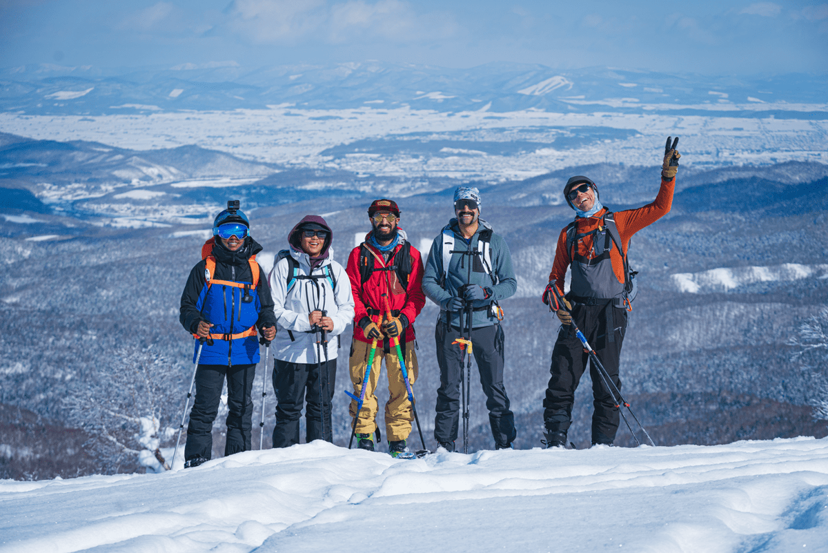 Woman snowboards deep powedr snow spraying in the birch trees of central hokkaido while on Guided Exposures annual Hokkaido Trip