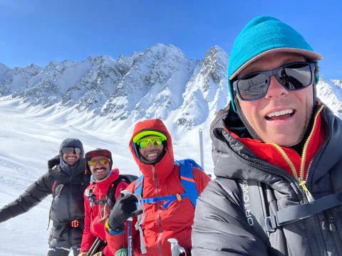 4 skiers in the sunny chugach mountains with snowy couloirs behind them