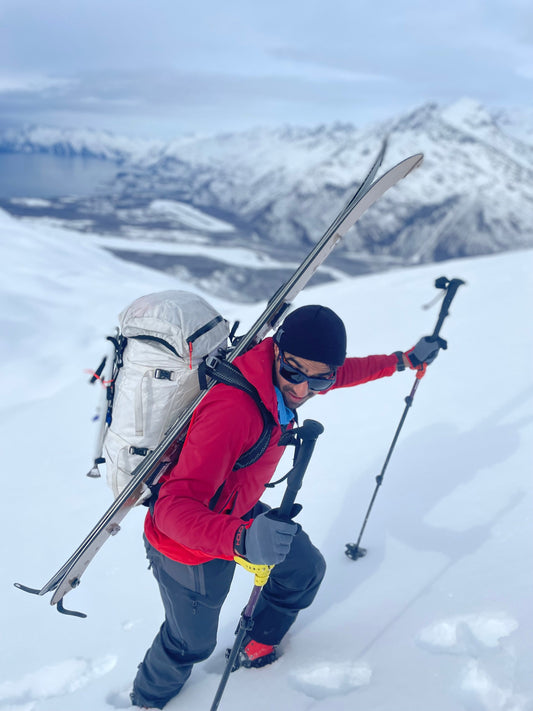 Skier with their boards quickly and easily sotwed behind their back while bootpacking in alaska