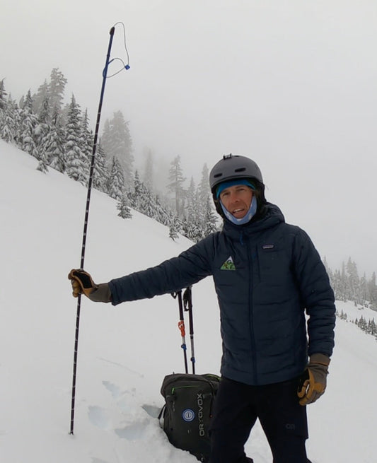 Using an avalanche probe to feel for layers with in the snowpack