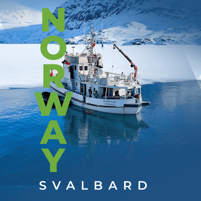 Ski tourers climbing a snowy Arctic peak above a glacier in Svalbard, Norway