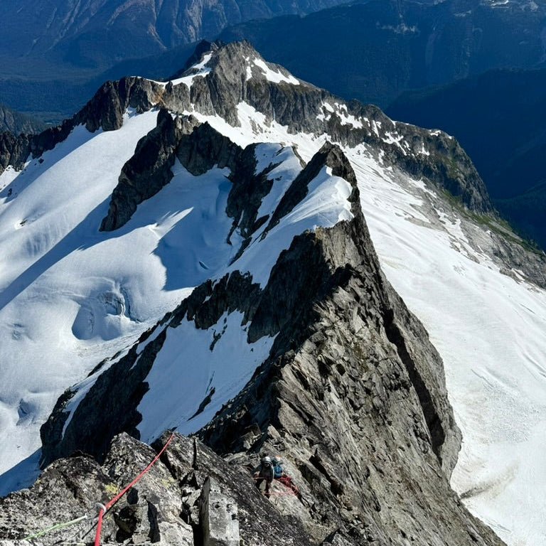 2 climbers have beautiful exposure on the lichen covered North Ridge of Forbidden Peak during a guided alpine climb with guided exposure in north cascades national park
