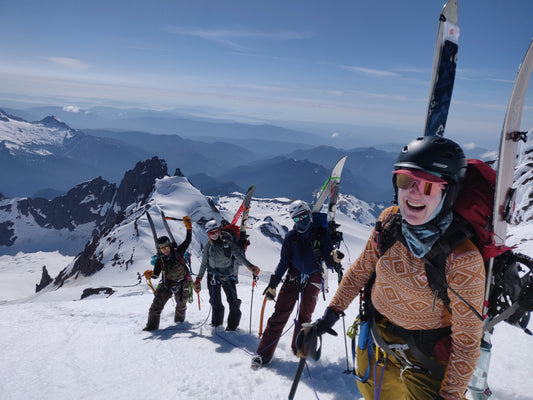 4 women with crampons, splitboards, and ice axes climb above colfax peak, the twin sisters, and bellingham while going up the pumice ridge and the roman wall on the coleman and deming glaciers on mount baker during the womens splitboard mountaineering course