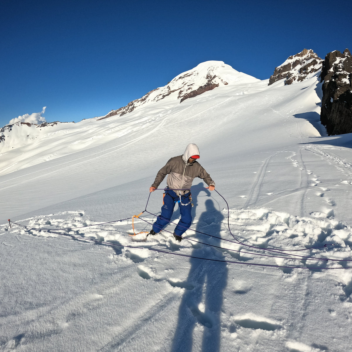 a splitboarder Practicing crevasse rescue at black buttes camp coleman glacier mount baker during a ski mountaineering trip 