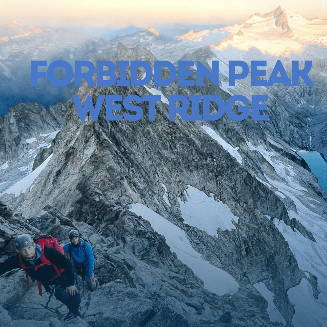 Two climbers on a mountain ridge with Forbidden Peak West Ridge