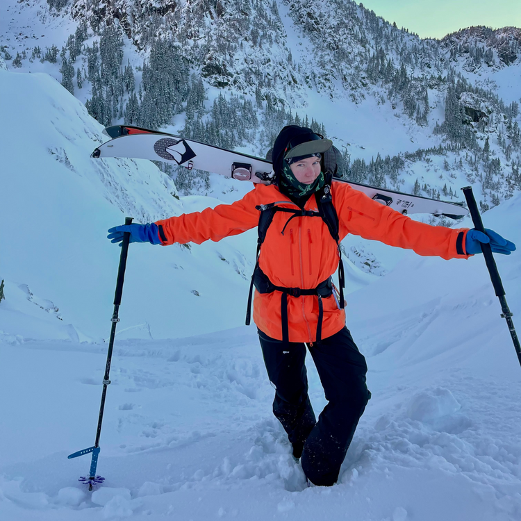 Women Ski Guide in an orange jacket with skis on a snowy mountain at mt baker ski area