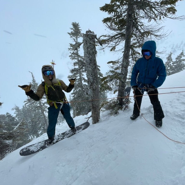 Two splitboarders celebrating on a snowy tree-lined slope during an Alaska ski and splitboard progression session