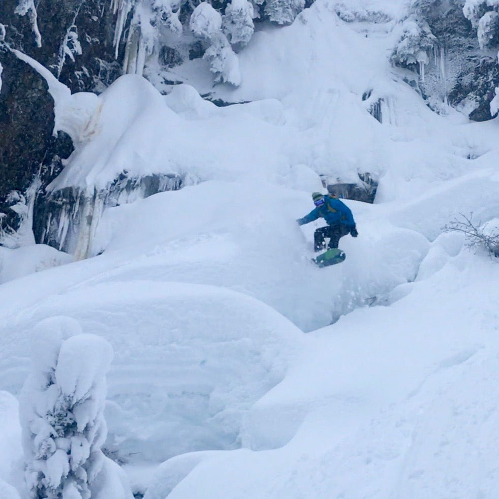 A snowboarder jumps of pillows of snow in the Mount Baker Backcountry during an advanced tour.