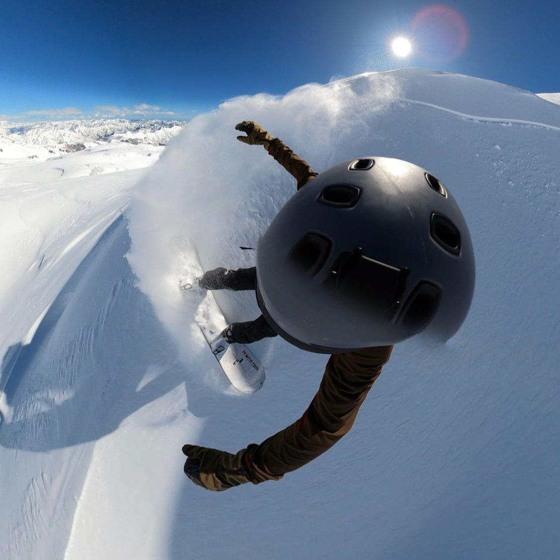 A snowboarder sprays powder on a sunny slope during a guided Chile summer ski trip in the Andes