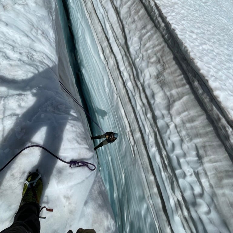 A climber belayed into a crevasse to practice rescue during a Glacier Travel Course at Mount Baker