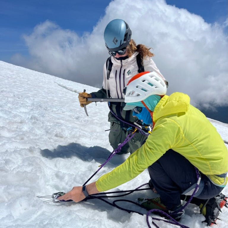A guide coaches a student on ice-axe and anchor skills during a Glacier Travel Course at Mount Baker