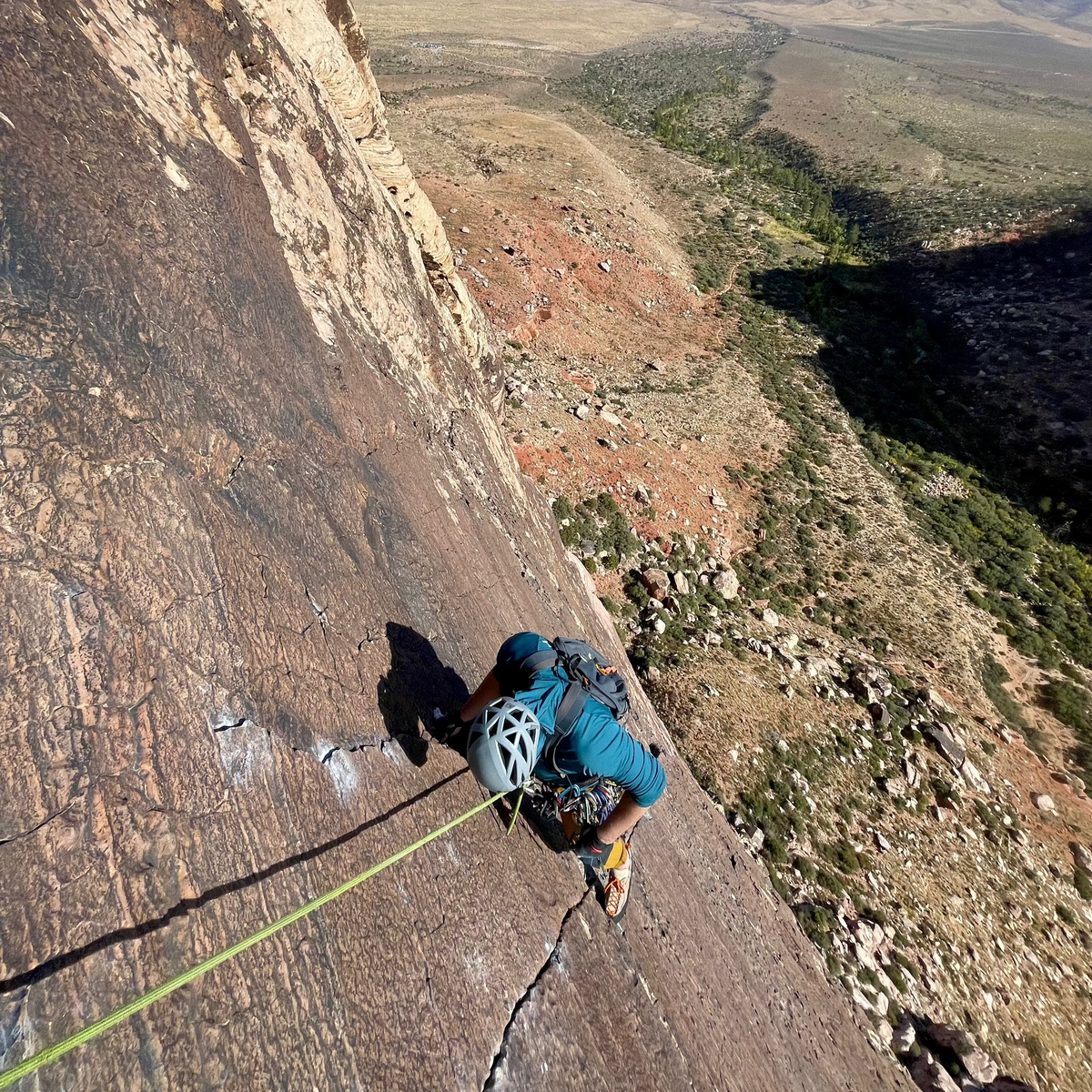 A climber on a long sandstone slab above the desert on a guided Red Rock Climbing Trip, Nevada