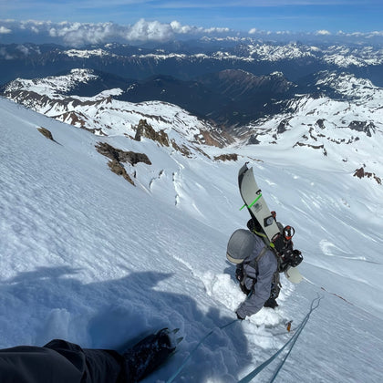 On the steepest section climbing the Park Headwall Mount Baker, with splitboard A-framed on pack, we get comfortable using a rope and crampons. during an advanced splitboard mountaineering course. Blue skies and Mountain views in the background. 