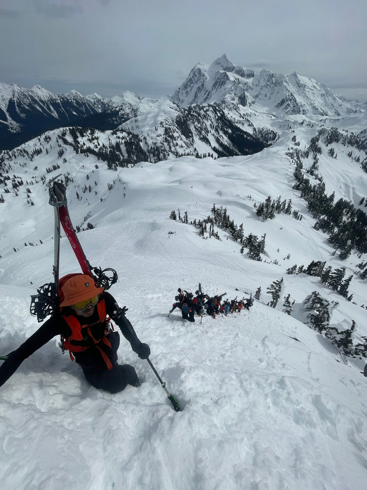 Splitboarder boot packing up a steep slope with shuksan standing tall in the background. The Mount Baker backcountry has nothing but impressive views to offer skiers and splitboards as they enjoy deep powder! 