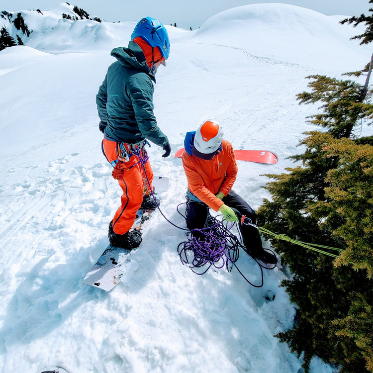 a splitboard guide belaying a snowboarder off a tree in the mount baker backcountry at artist point