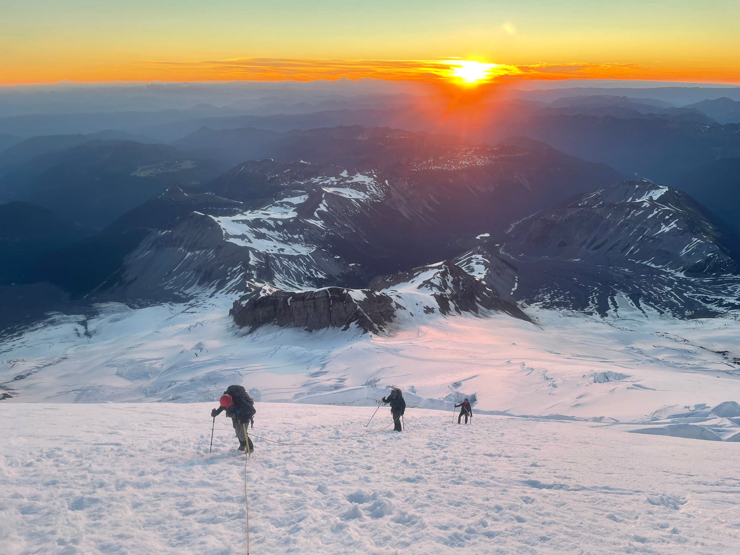 Sunrise over the Emmons Glacier as mountaineers climb the glacier
