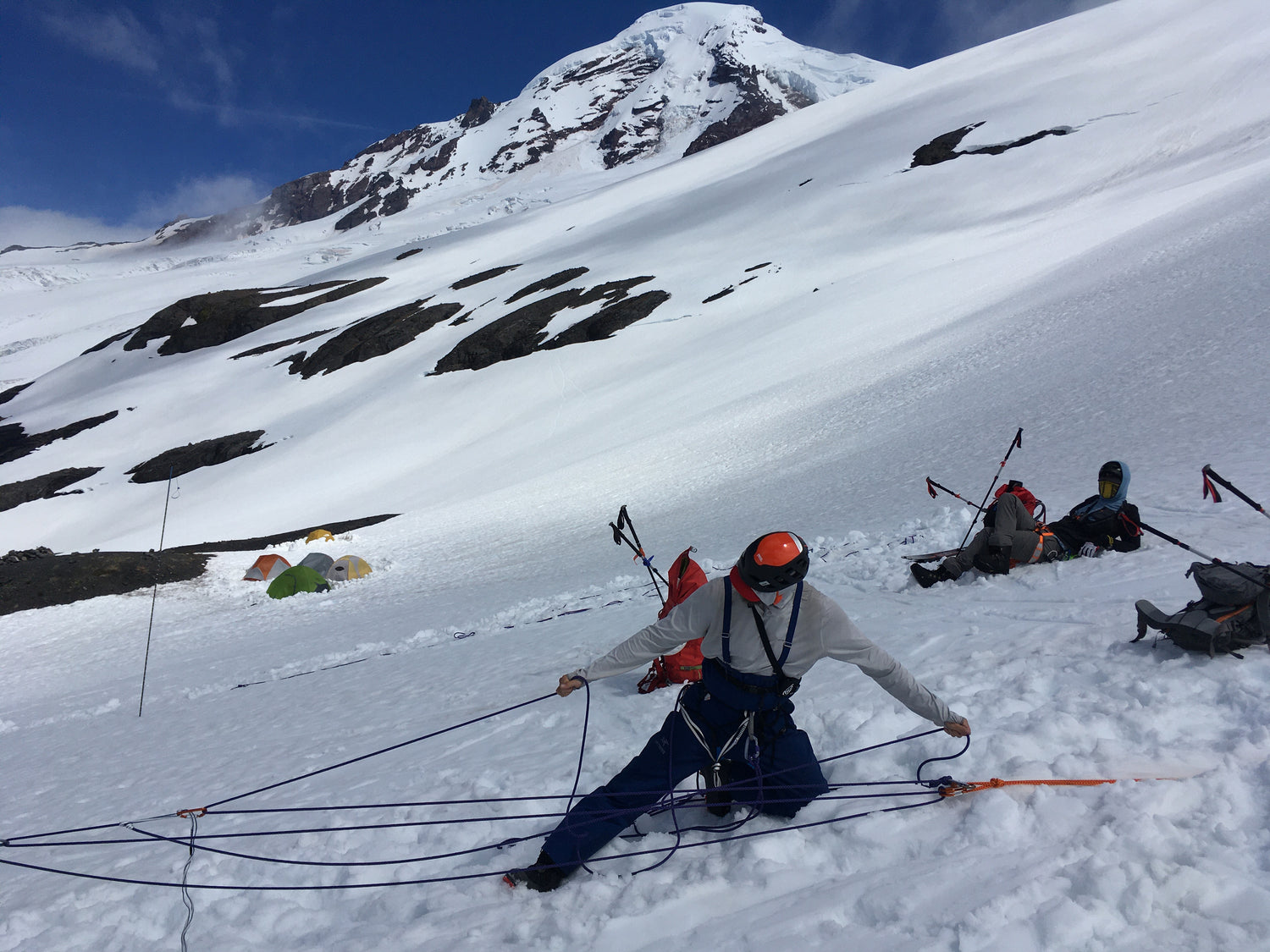 Climber practices Crevasse recuse systems on the side of Mount Baker with the mountain in the background. 