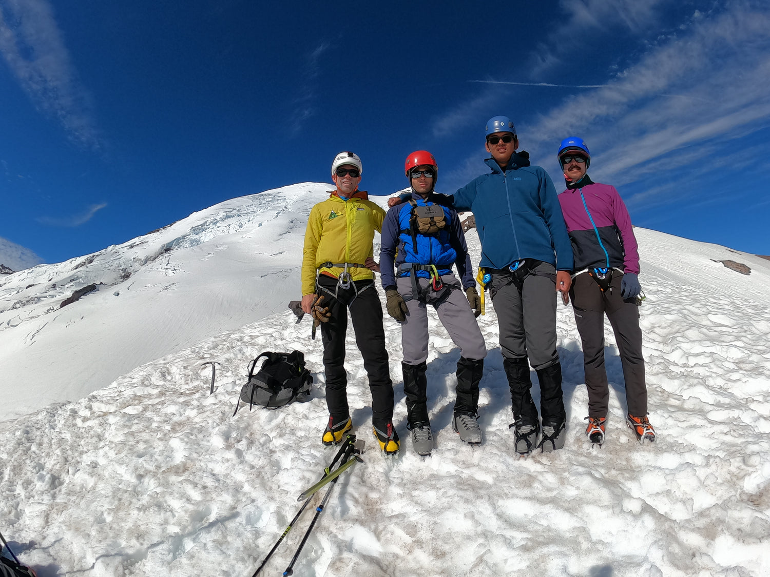 the summit of mount rainier sits behind the climbing team on top of the interglacier