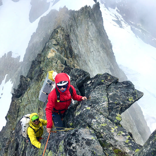 2 climbers have beautiful exposure on the lichen covered North Ridge of Forbidden Peak during a guided alpine climb with guided exposure in north cascades national park