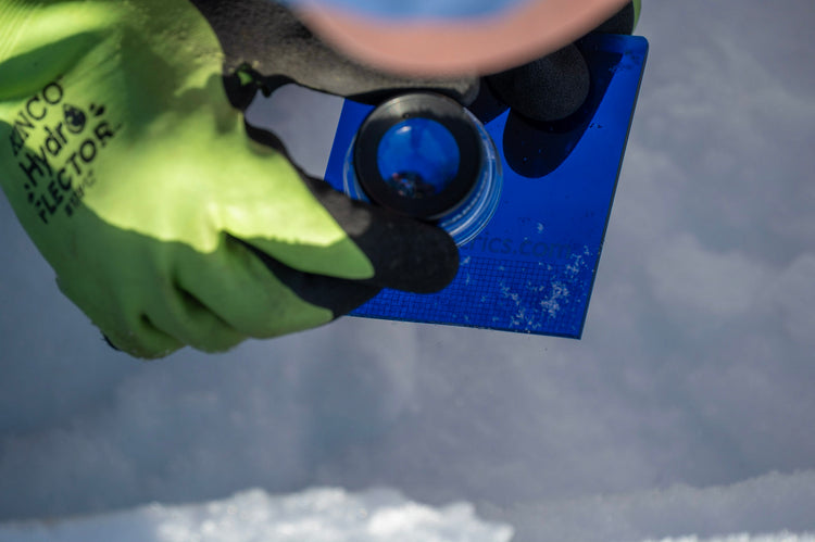 This is what looking at individual snow grains is like. Snow is on the blue plastic crystal card and you look at the grains through a magnifying glass called a loupe.
