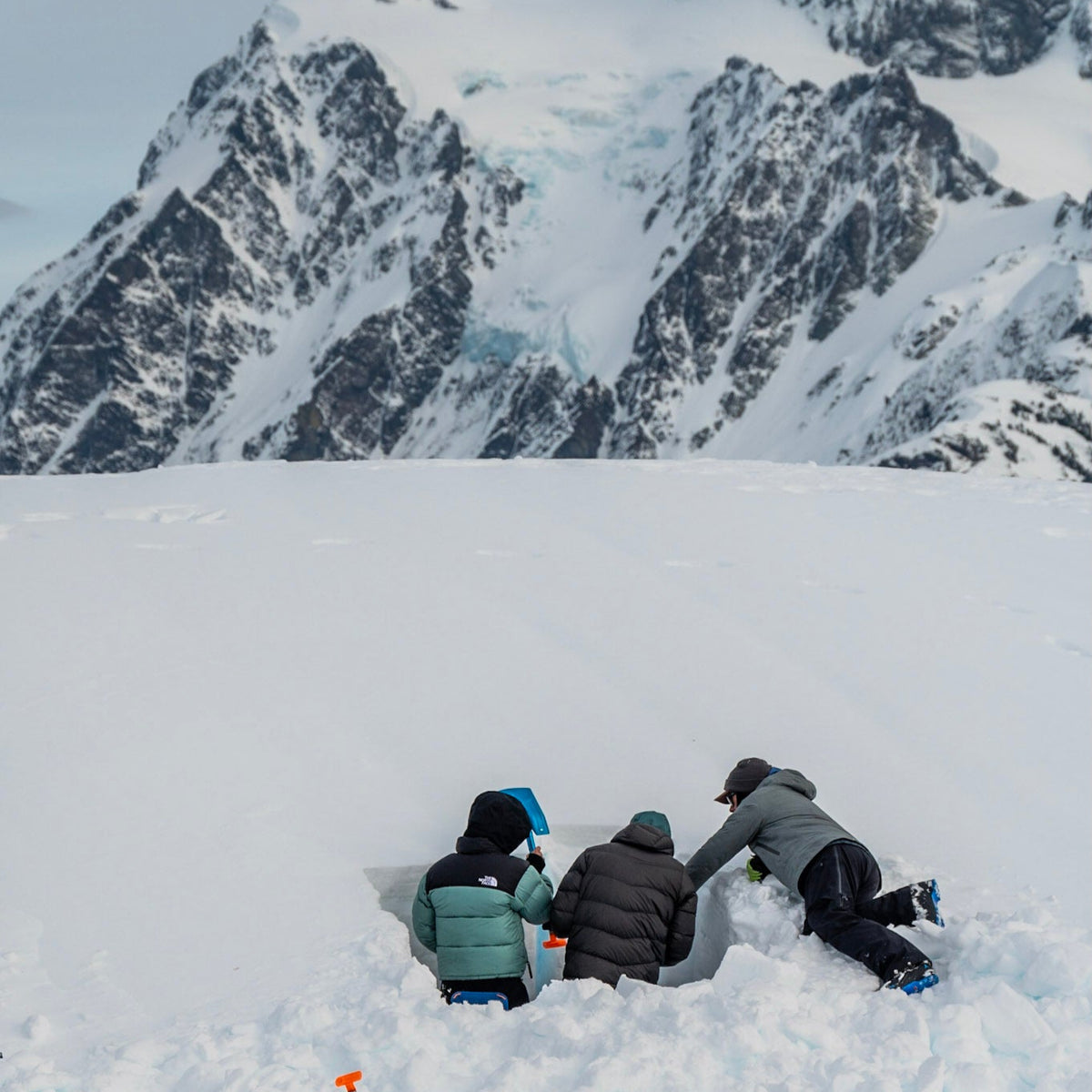 AIARE 1 students get feedback on their snow profile from the Lead Guide at Guided Exposure. Mount Shuksan stand tall in the background on a stunning day in the Mount Baker Backcountry.  