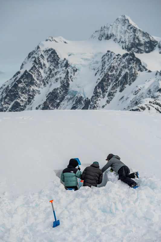 AIARE 1 students get feedback on their snow profile from the Lead Guide at Guided Exposure. Mount Shuksan stand tall in the background on a stunning day in the Mount Baker Backcountry.  