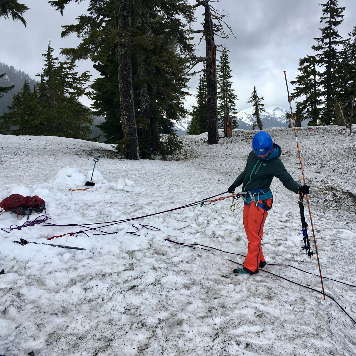 Student probes for the edge of a steep embankment to get ready for rappelling. 