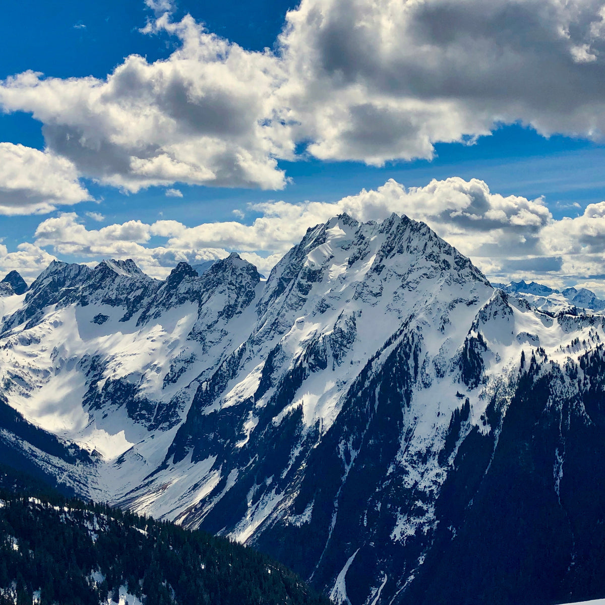 blue skies and broken clouds cast sunlights on the snow and glacier covered slopes of johannesburg mountain with in north cascades national park during guided exposure forbidden tour