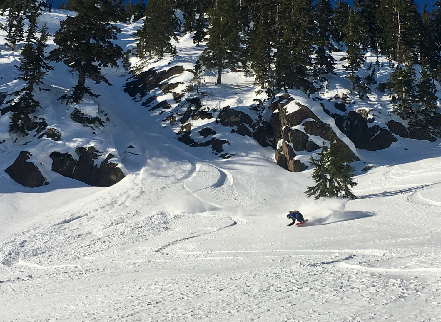 A splitboarder making a deep turn coming out of a rocky chute. During the Advanced Splitboard course we ride a variety of terrain!