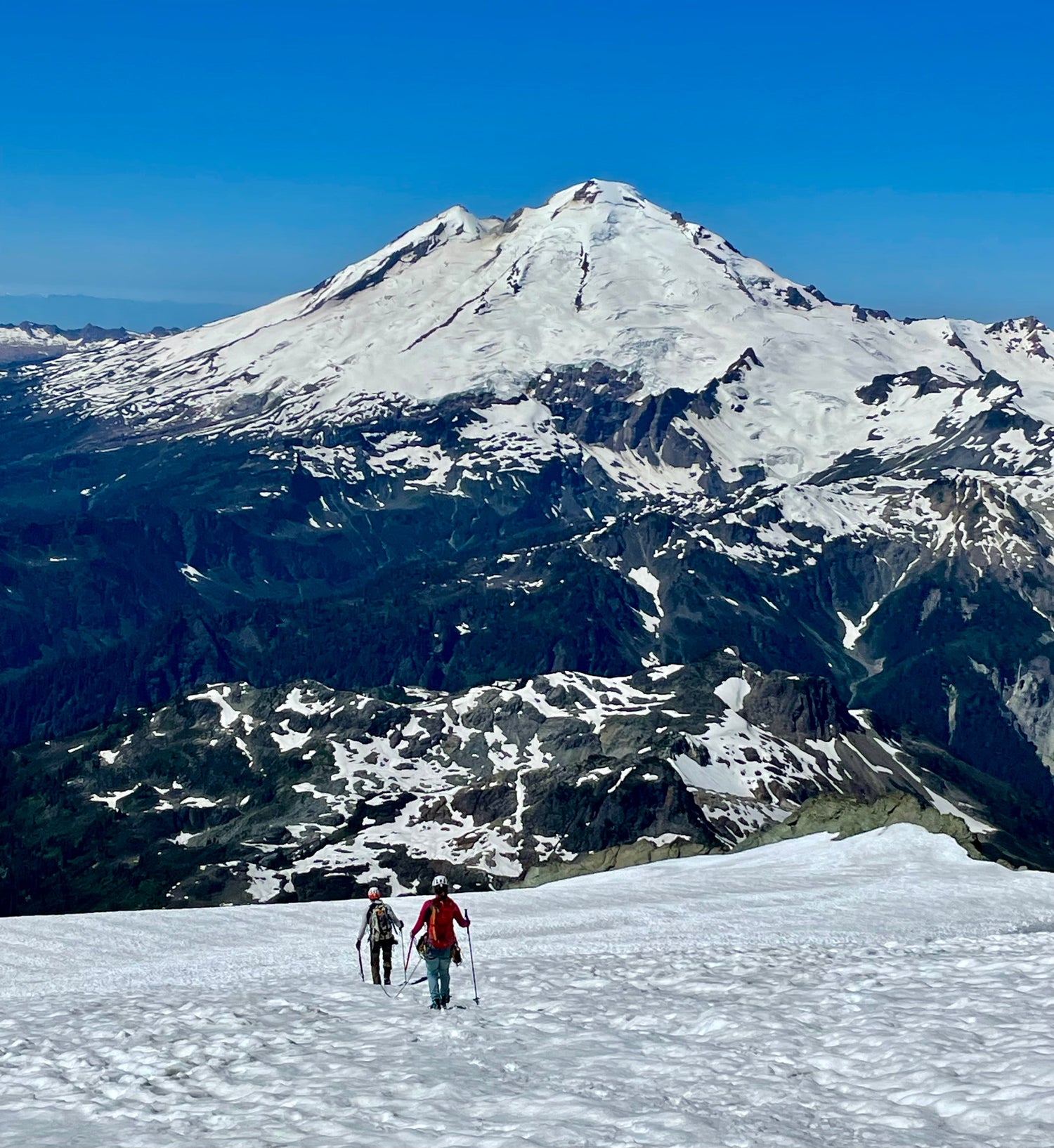 Climbers walking down after a successful summit, with views of Mount Baker in the background.  