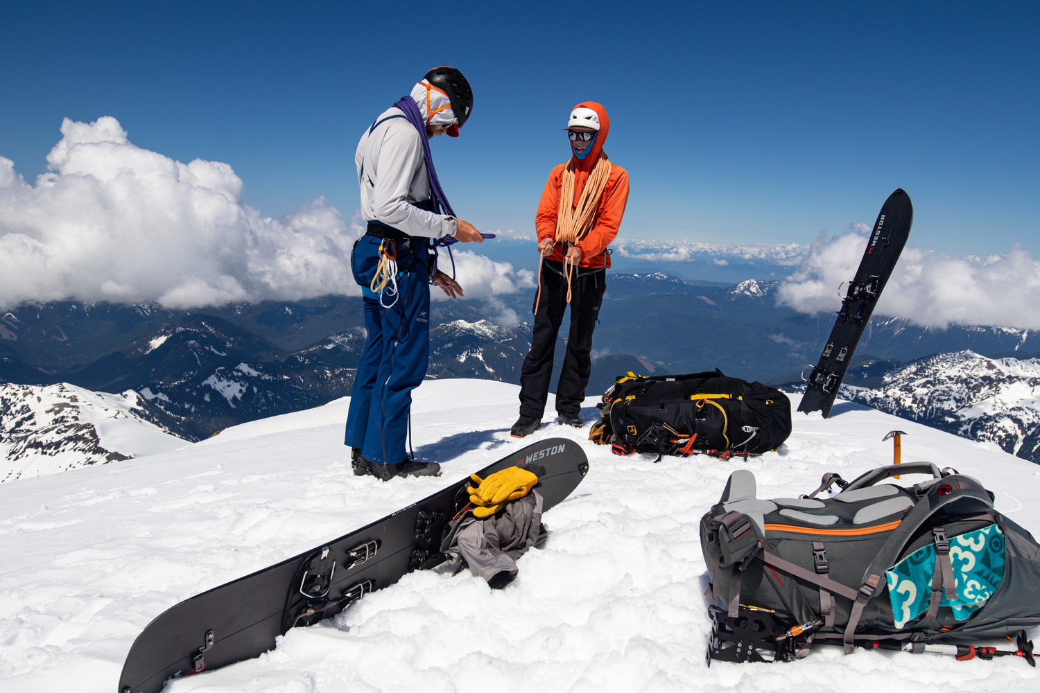 During the advanced splitboard course participants learn how to ride with ropes for complex glacial descents. Splitboard Guide Jere Burrell demonstrates how to kiwi coil a rope while ion the summit of Colfax Peak on Mount Baker. 