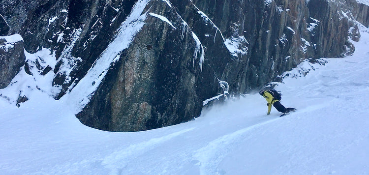 A splitboarder making a toe side turn with beautiful cliffs behind them in the Mount Baker backcountry. 