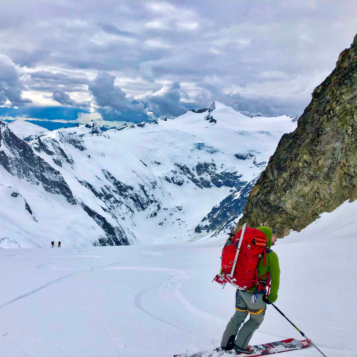 Ski mountaineer with skis on their pack looking out over a glaciated valley during a 4-day ski mountaineering course at Mount Baker